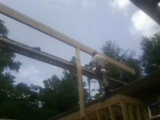 Carpenter setting a ridge beam over a new addition frame — Ice Dam Removal by Roofing Brothers in Deal Island