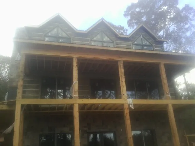 Dormers and porch framing on a large log home under construction — Roof Coating work by our crew in Deal Island