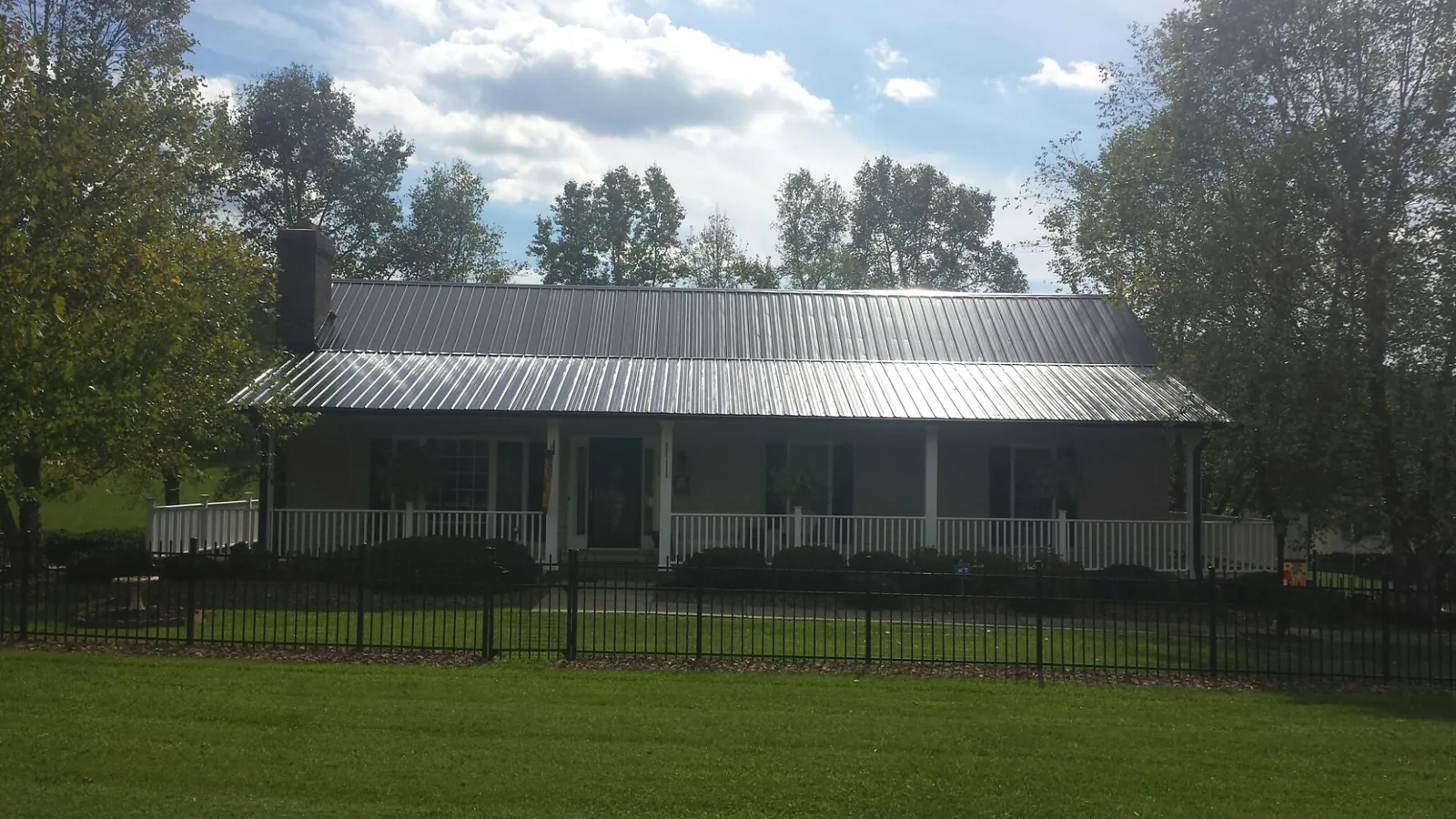 Gray metal roof on a brick ranch with a full width front porch — Gutter Guard Installation work by our crew in Deal Island