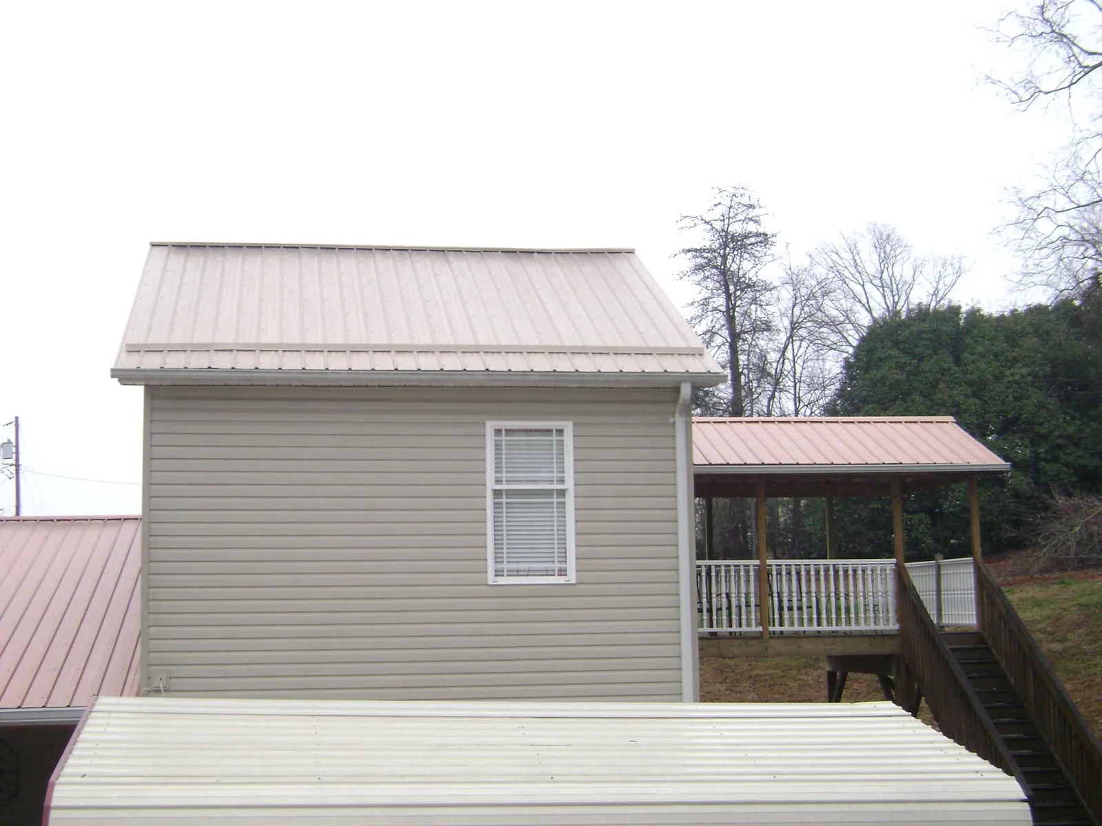 Tan metal roofs on a two story addition and attached porch, from a Roof Replacement job in Deal Island