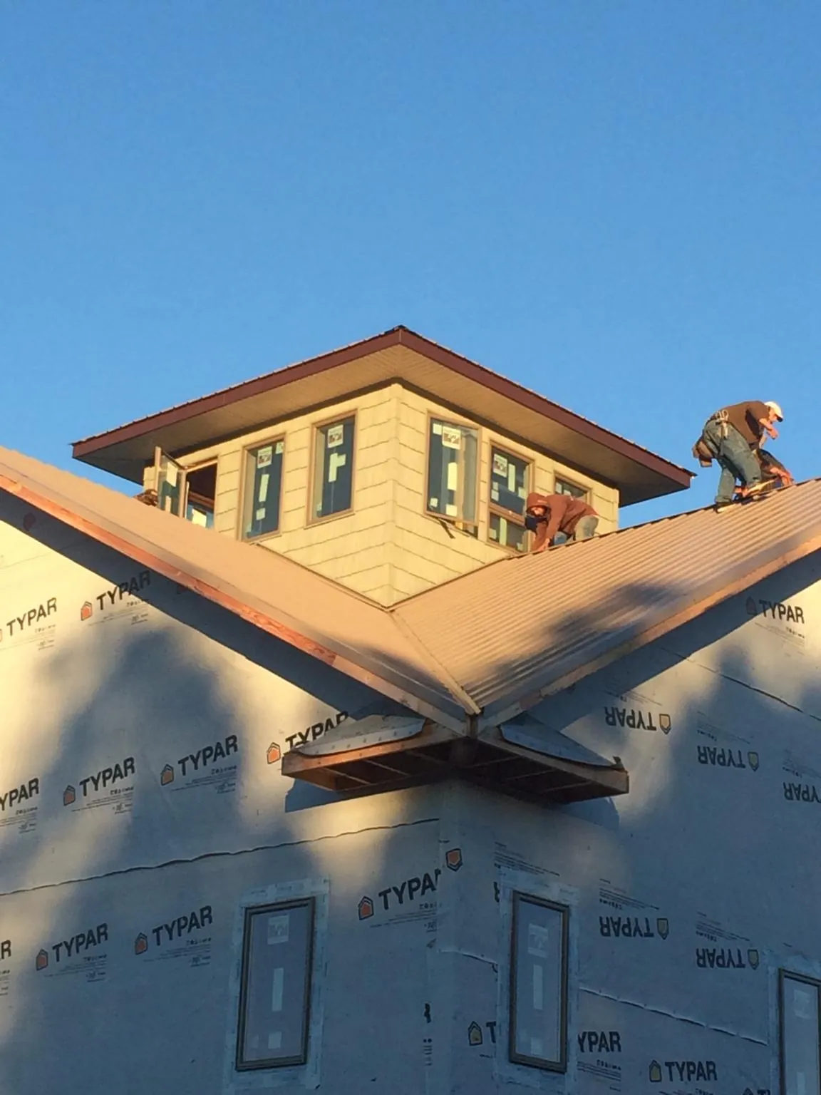 Roofers working around a rooftop cupola on a new metal roof at sunset — Roof Waterproofing in Deal Island by Roofing Brothers